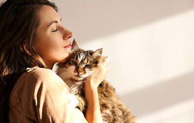 Frau kuschelt mit Katze auf dem Arm